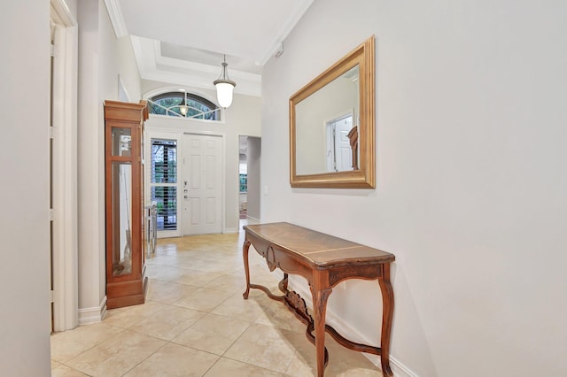 tiled foyer with a raised ceiling and crown molding