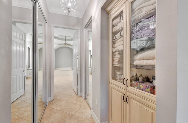 corridor featuring light tile patterned floors and ornamental molding