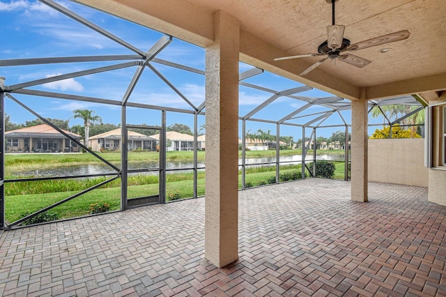 view of patio / terrace featuring a water view, glass enclosure, and ceiling fan