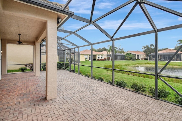 view of patio featuring a lanai, ceiling fan, and a water view