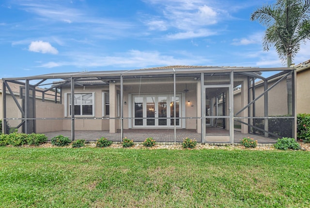 rear view of property with glass enclosure, a patio area, and a yard