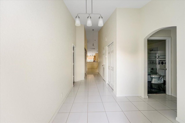 hallway with light tile patterned floors and a high ceiling