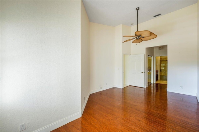 spare room featuring ceiling fan, dark hardwood / wood-style flooring, and a towering ceiling