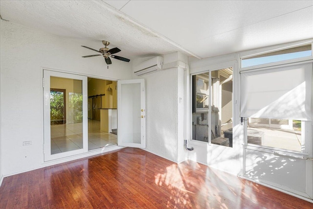 spare room featuring hardwood / wood-style floors, a textured ceiling, an AC wall unit, and ceiling fan