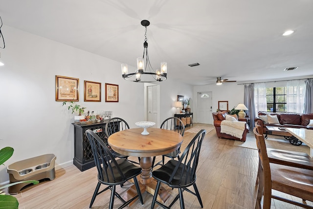 dining area with ceiling fan with notable chandelier and light wood-type flooring