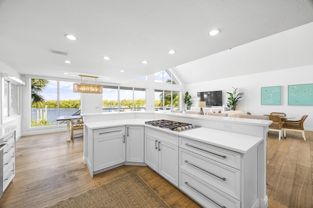 kitchen with white cabinets, stainless steel gas stovetop, plenty of natural light, and light hardwood / wood-style flooring