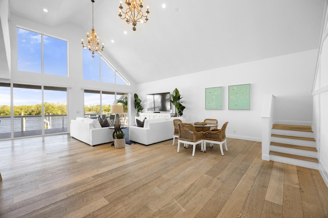 living room featuring light wood-type flooring, high vaulted ceiling, and a notable chandelier