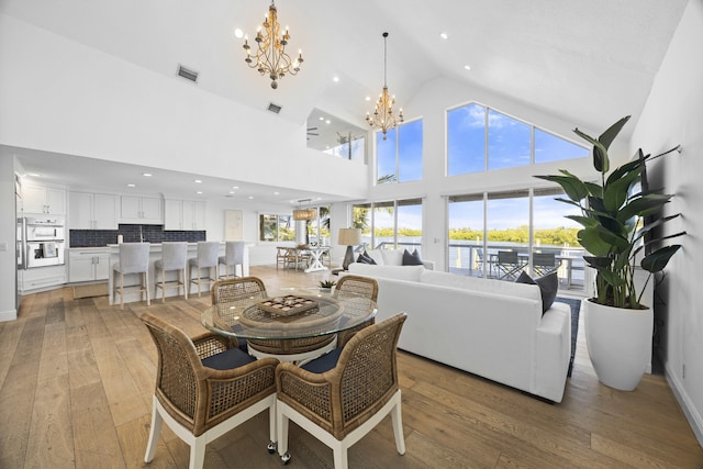 dining room featuring high vaulted ceiling, wood-type flooring, and a notable chandelier