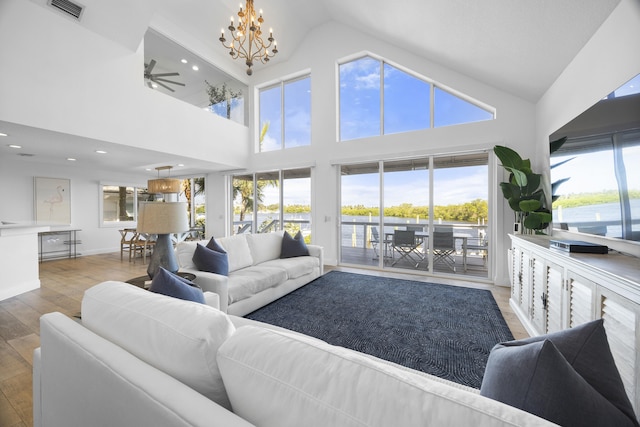 living room featuring a wealth of natural light, ceiling fan with notable chandelier, high vaulted ceiling, and light hardwood / wood-style flooring