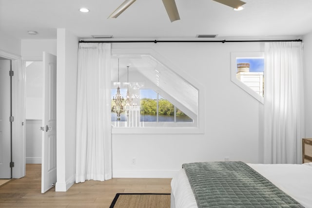 bedroom with ceiling fan with notable chandelier, light hardwood / wood-style flooring, and lofted ceiling