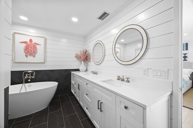 bathroom featuring a bath, vanity, and wooden walls