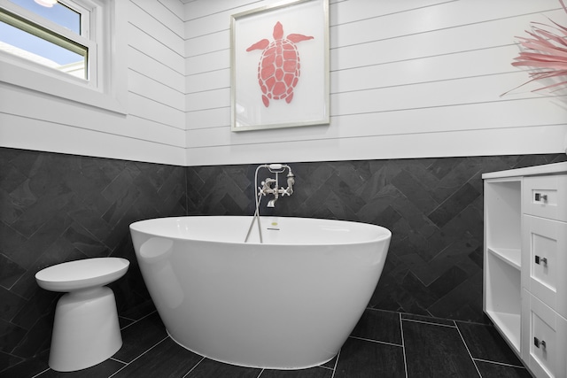 bathroom with tile patterned flooring, tile walls, and a tub