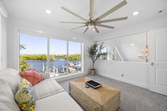 carpeted living room featuring ceiling fan with notable chandelier, a water view, a wealth of natural light, and lofted ceiling