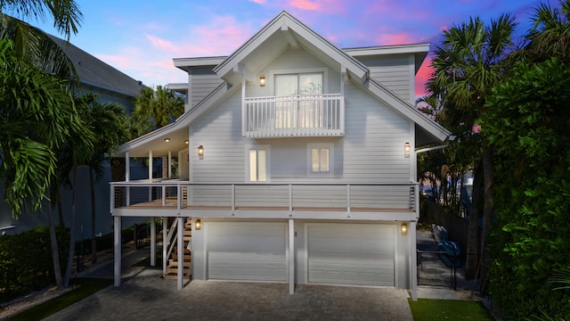 back house at dusk with a balcony and a garage