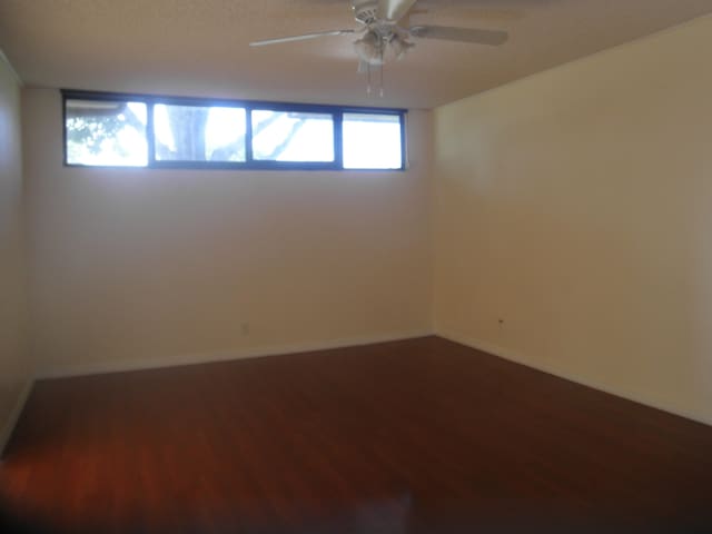 spare room with dark hardwood / wood-style flooring and ceiling fan