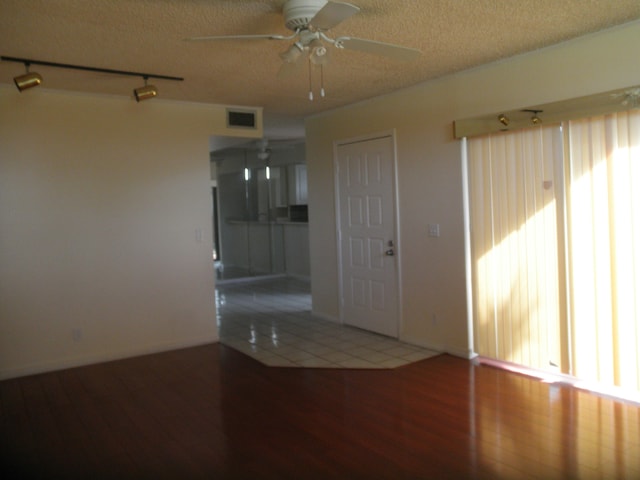 spare room with track lighting, a textured ceiling, hardwood / wood-style flooring, and ceiling fan