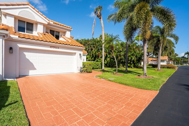 mediterranean / spanish house featuring a front yard and a garage