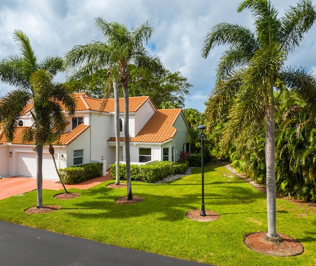 mediterranean / spanish home featuring a front yard and a garage