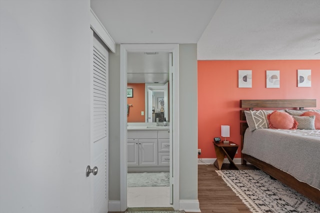 bedroom featuring ensuite bath and hardwood / wood-style floors