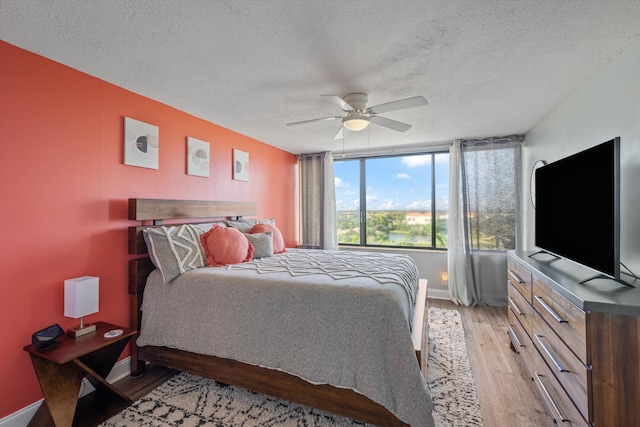 bedroom featuring ceiling fan, light wood-type flooring, and a textured ceiling