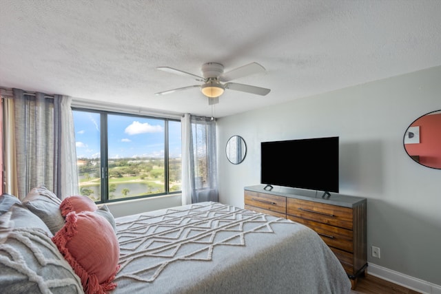 bedroom featuring ceiling fan, wood-type flooring, and a textured ceiling