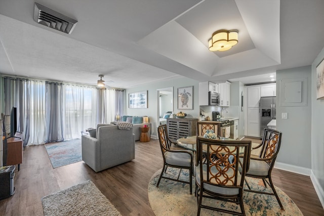 dining space featuring dark hardwood / wood-style floors, a raised ceiling, and ceiling fan