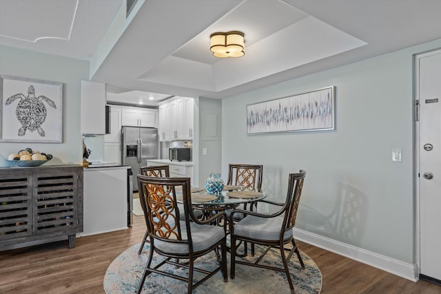 dining space with a tray ceiling and dark hardwood / wood-style floors