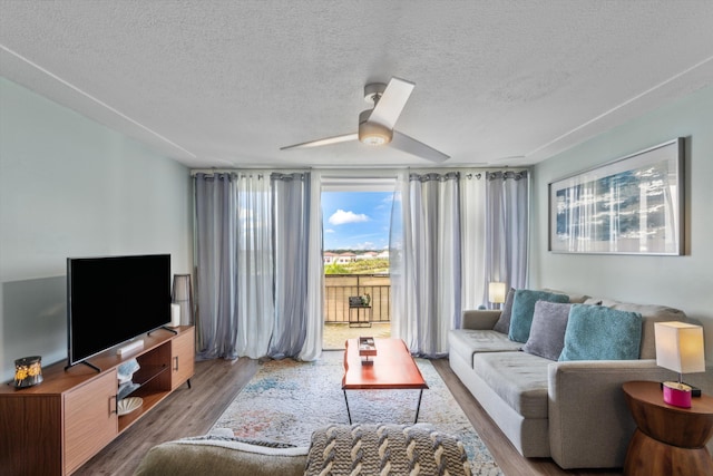 living room with ceiling fan, a textured ceiling, and hardwood / wood-style flooring