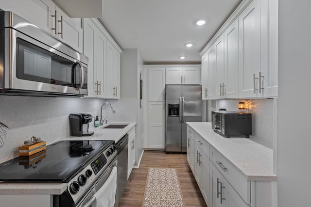 kitchen featuring hardwood / wood-style floors, stainless steel appliances, white cabinetry, and sink