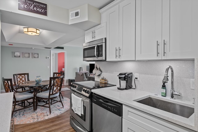 kitchen with white cabinetry, sink, dark hardwood / wood-style floors, light stone countertops, and stainless steel appliances