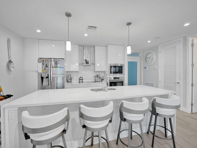 kitchen with decorative light fixtures, white cabinetry, light hardwood / wood-style flooring, and stainless steel appliances