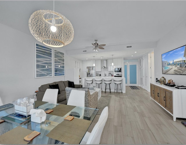 dining room featuring ceiling fan with notable chandelier and light wood-type flooring