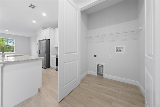 clothes washing area featuring light hardwood / wood-style floors, hookup for a washing machine, hookup for an electric dryer, and sink