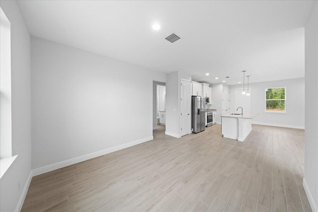 unfurnished living room featuring sink and light hardwood / wood-style flooring