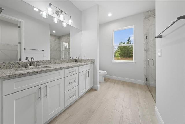 bathroom with toilet, vanity, hardwood / wood-style floors, and a shower with door