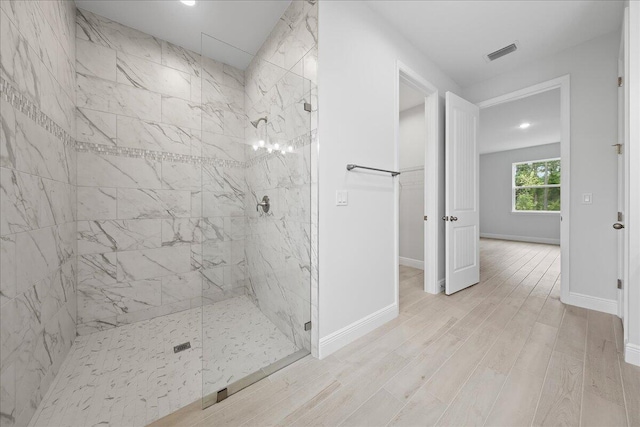 bathroom with hardwood / wood-style floors and a tile shower