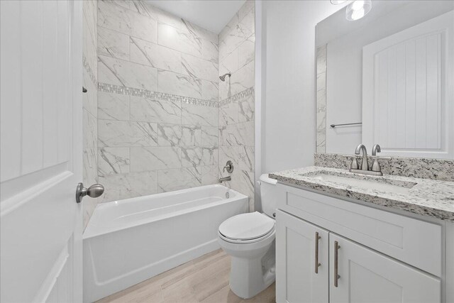 full bathroom with toilet, vanity, tiled shower / bath, and hardwood / wood-style floors