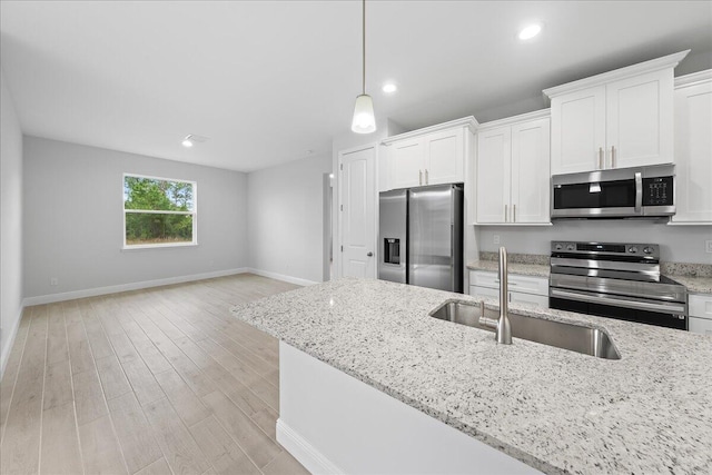 kitchen with stainless steel appliances, light stone counters, hanging light fixtures, white cabinets, and light wood-type flooring