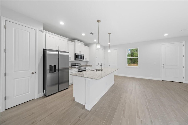 kitchen featuring stainless steel appliances, white cabinetry, light hardwood / wood-style flooring, sink, and a kitchen island with sink