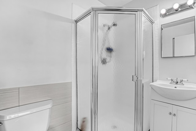 bathroom with vanity, a shower with shower door, tile walls, and toilet