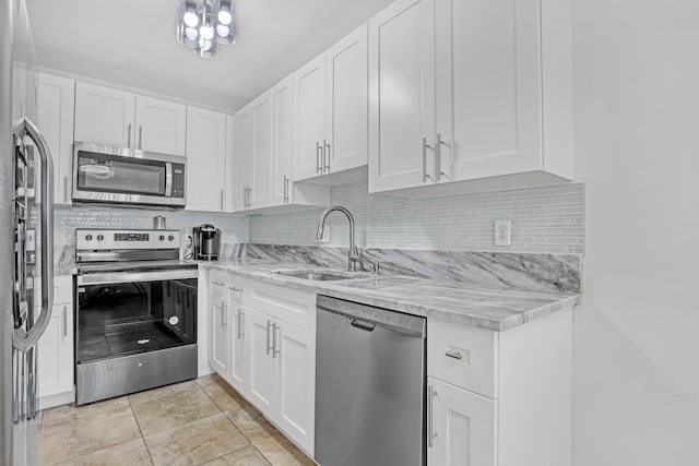 kitchen with sink, stainless steel appliances, light tile patterned floors, tasteful backsplash, and white cabinets