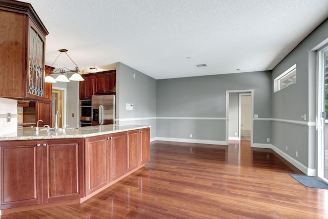 kitchen with stainless steel appliances, dark wood-type flooring, and a textured ceiling