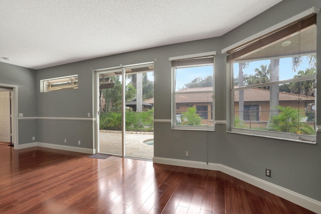 unfurnished room with wood-type flooring and a textured ceiling