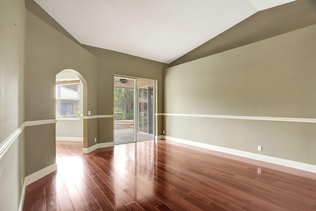 empty room featuring hardwood / wood-style floors, a textured ceiling, and vaulted ceiling