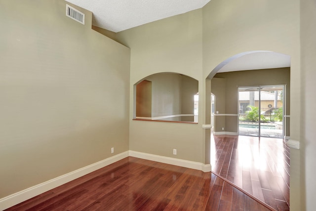 unfurnished room featuring hardwood / wood-style floors, a textured ceiling, and high vaulted ceiling