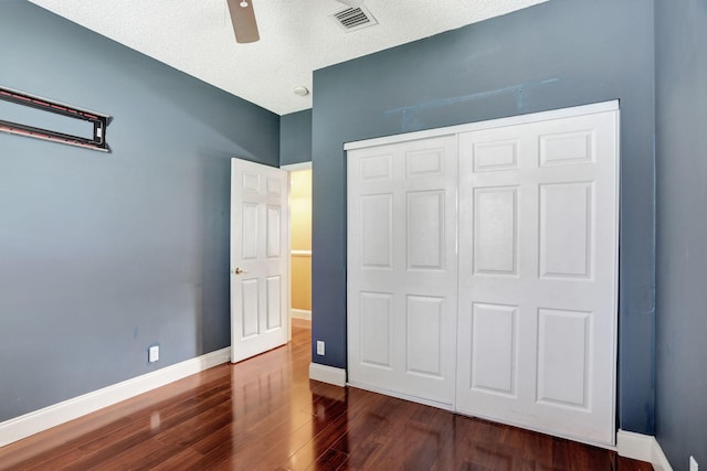 unfurnished bedroom featuring ceiling fan, dark hardwood / wood-style floors, a textured ceiling, and a closet