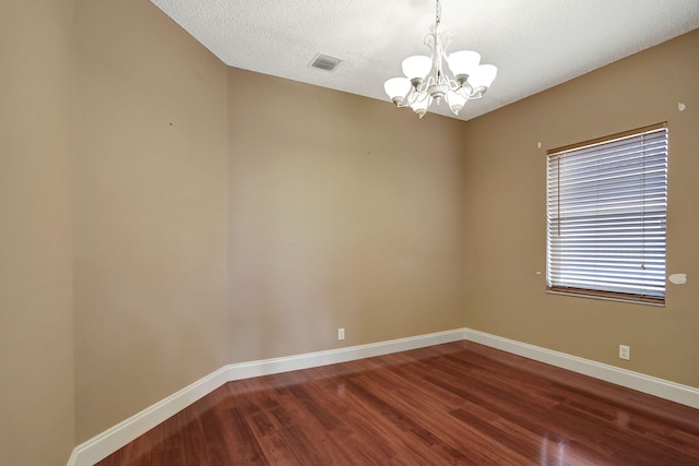 empty room with hardwood / wood-style floors, a chandelier, and a textured ceiling