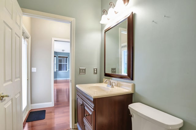 bathroom featuring wood-type flooring, toilet, and vanity