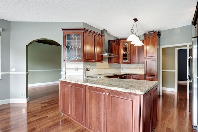 kitchen featuring pendant lighting, wall chimney exhaust hood, sink, and dark hardwood / wood-style flooring