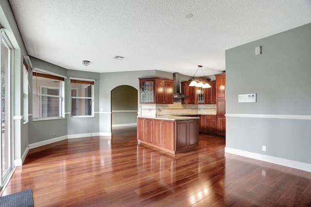 kitchen with dark hardwood / wood-style flooring, wall chimney exhaust hood, hanging light fixtures, a textured ceiling, and tasteful backsplash